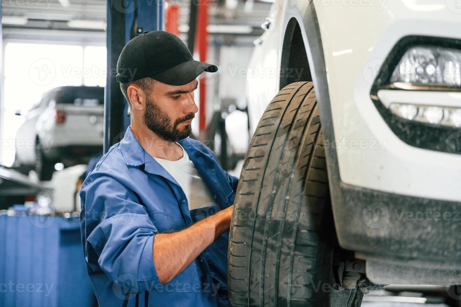 Setting, up new wheel. Auto mechanic working in garage. Repair service photo