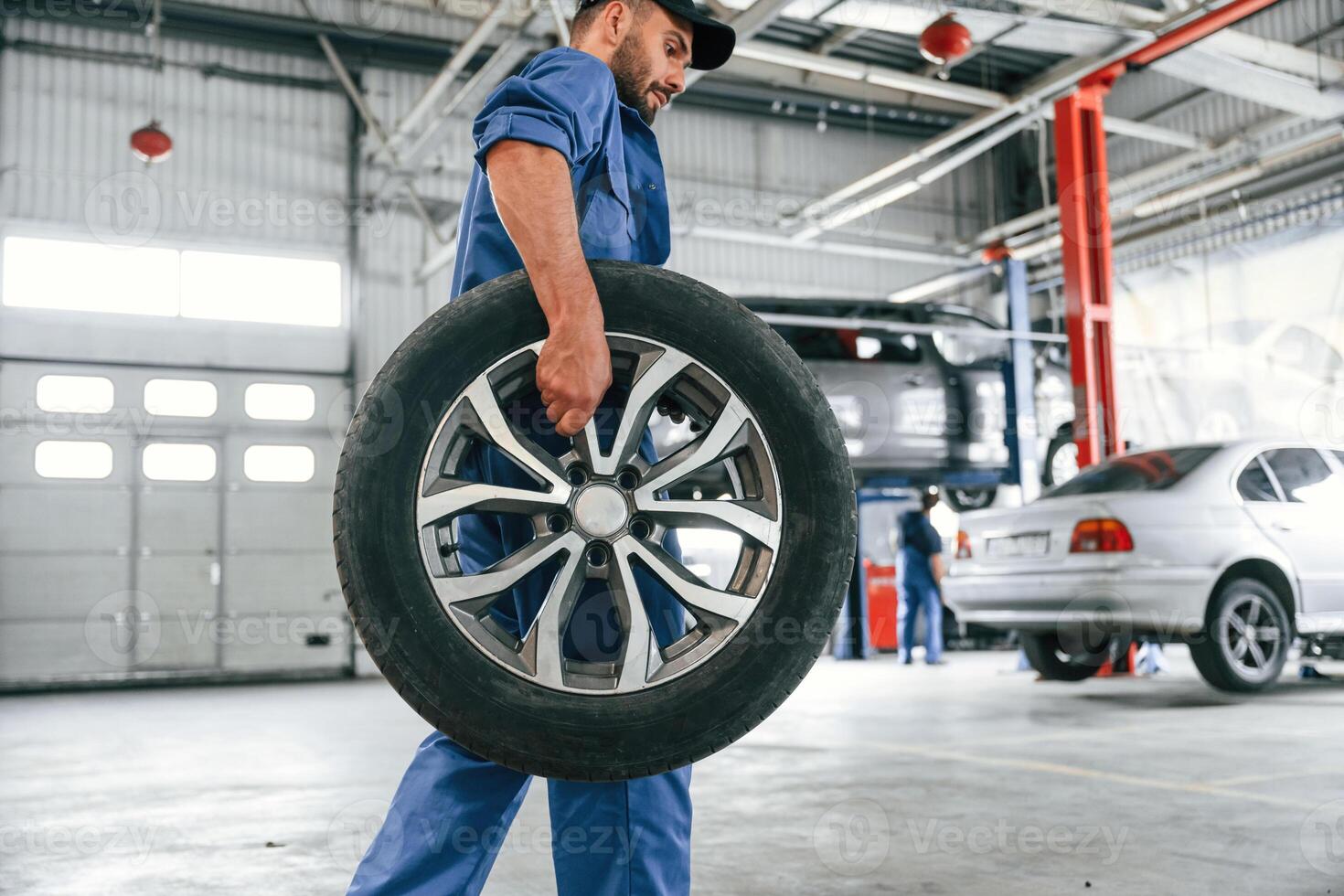 With, brandm new wheel. Auto mechanic working in garage. Repair service photo