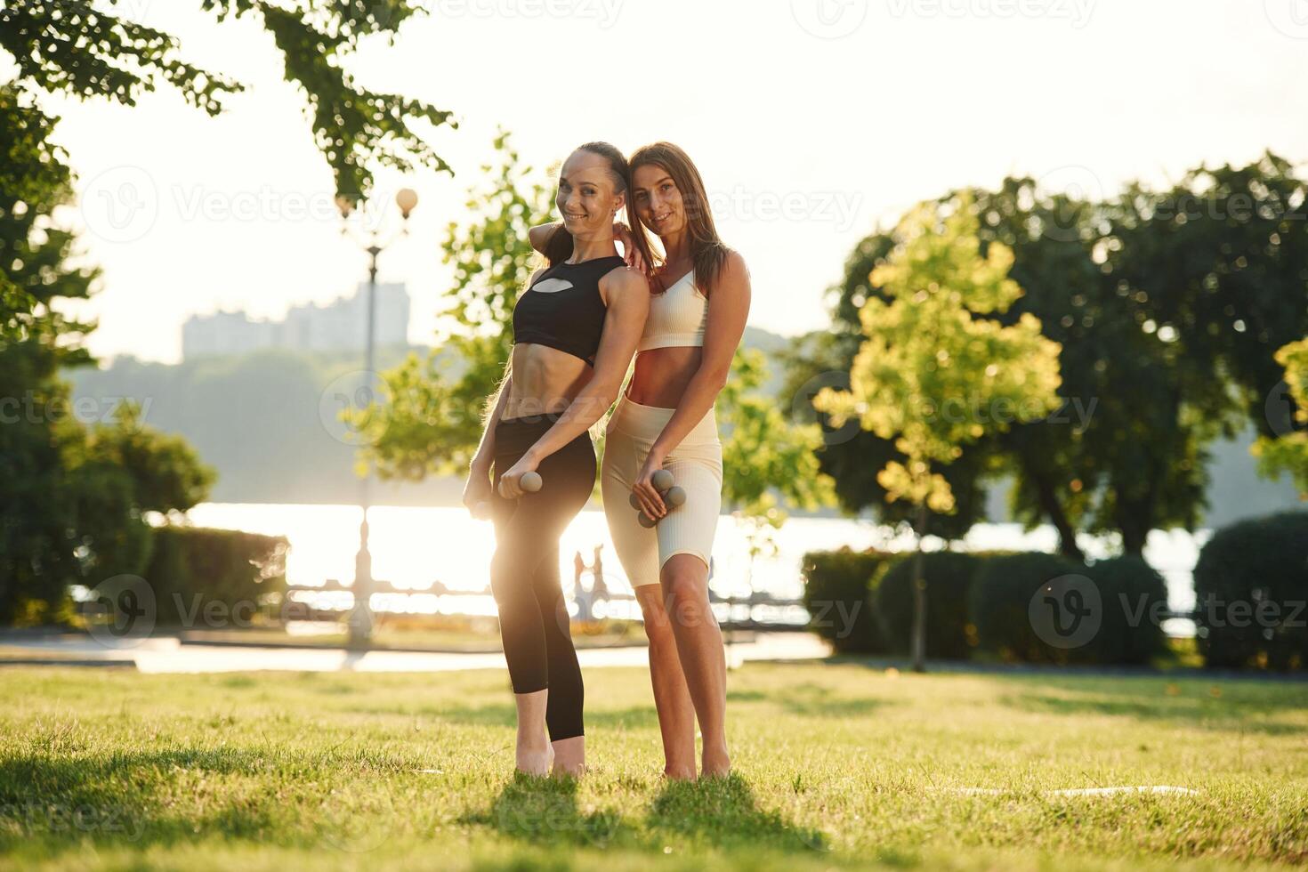 Standing ,and, posing. Two women in sport clothes are doing exercises outdoors on the field photo