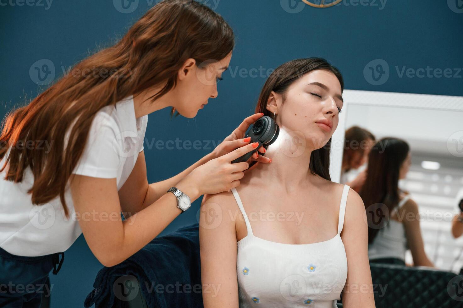 Beauty ,salon ,worker, is examining skin of the woman by using a device with light and lens photo