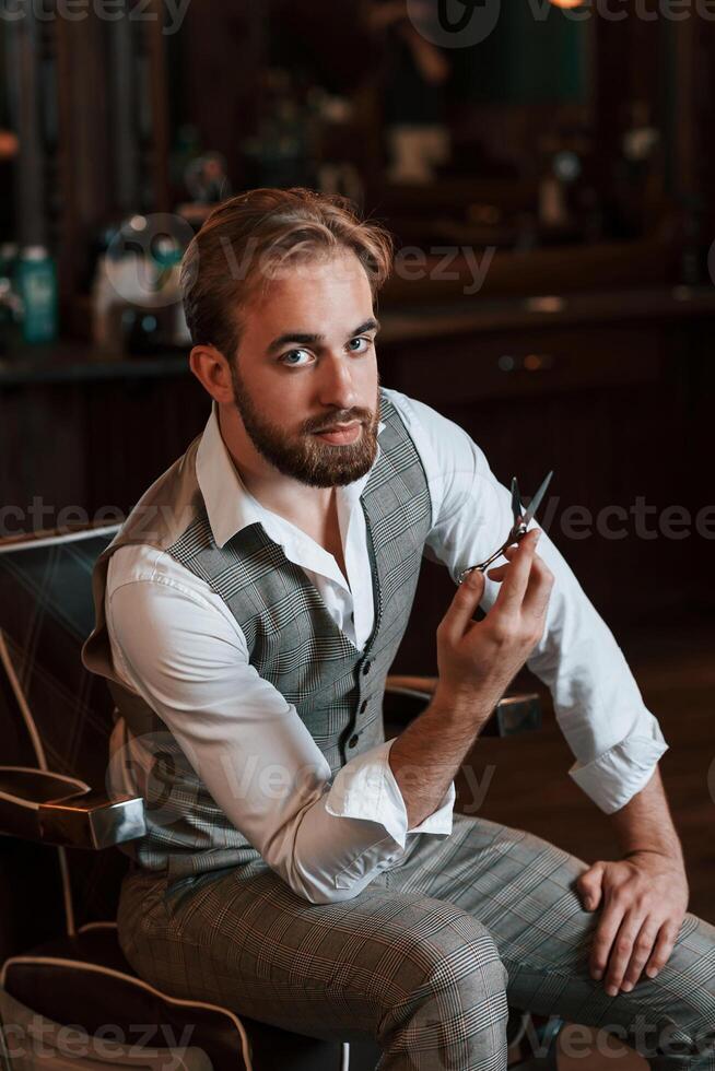 Holding, scissors. Handsome, barber ,is in the salon photo