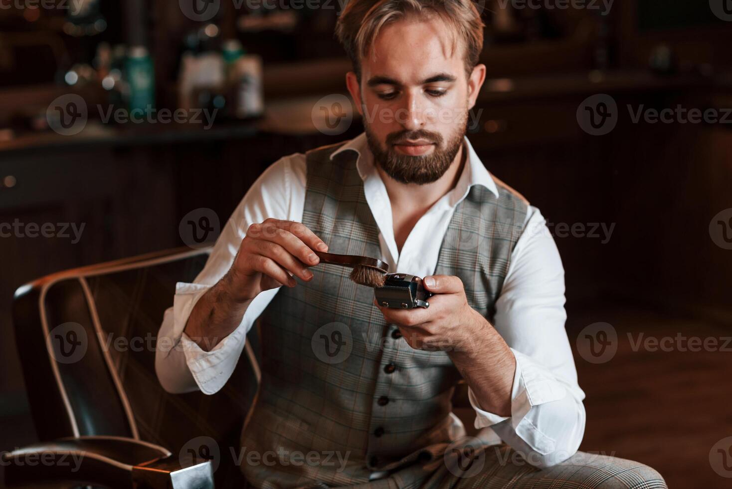 Cleaning hair clipper. Handsome barber, is ,in the salon photo