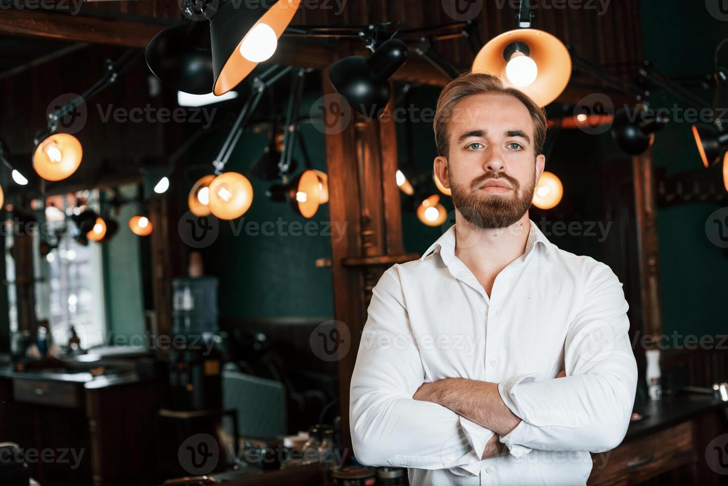 Standing with ,arms crossed. Handsome, barber is in the salon photo