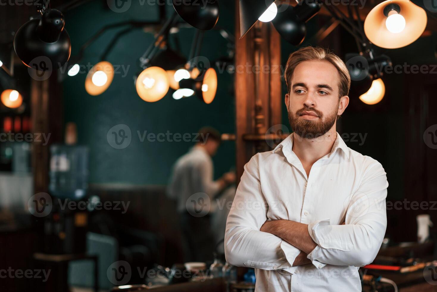 Standing with arms crossed.. Handsome barber is in the salon photo