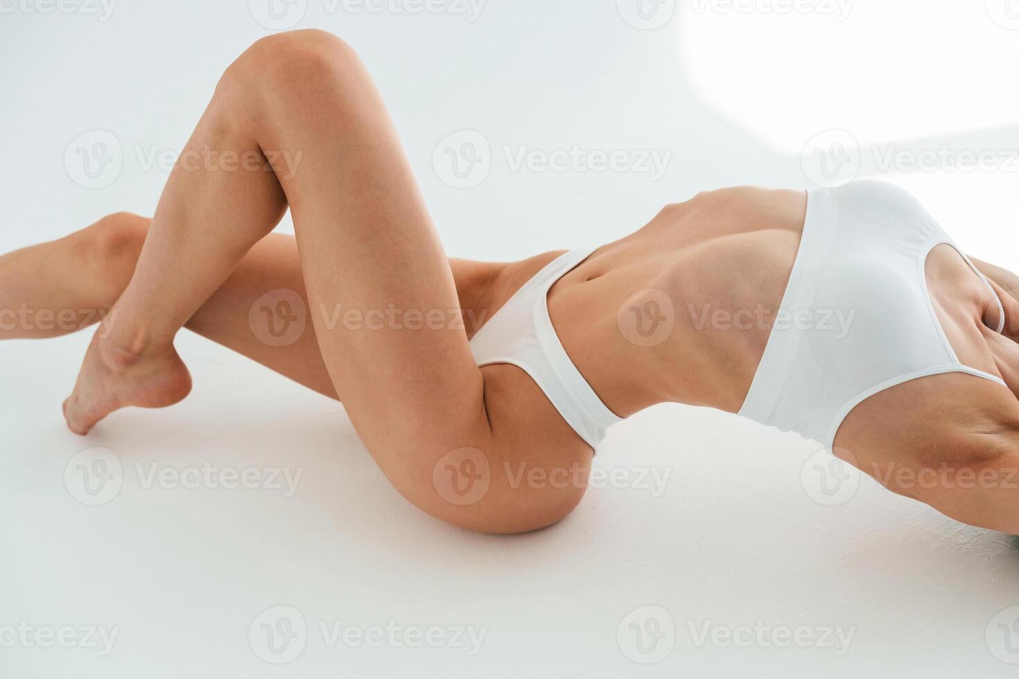 Close up view ,of belly, on the floor. Young woman with slim body type is in fitness clothes in the studio photo