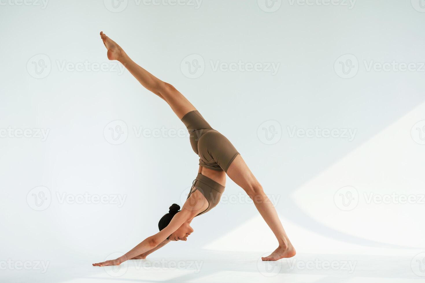 Working on the ,stretching of legs. Young woman with slim body type is in fitness clothes in the studio photo