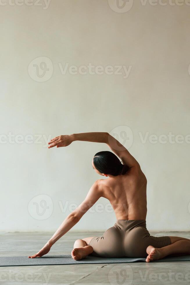 Flexible ,body, sitting, rear view. Young woman with slim body type is in fitness clothes in the studio photo