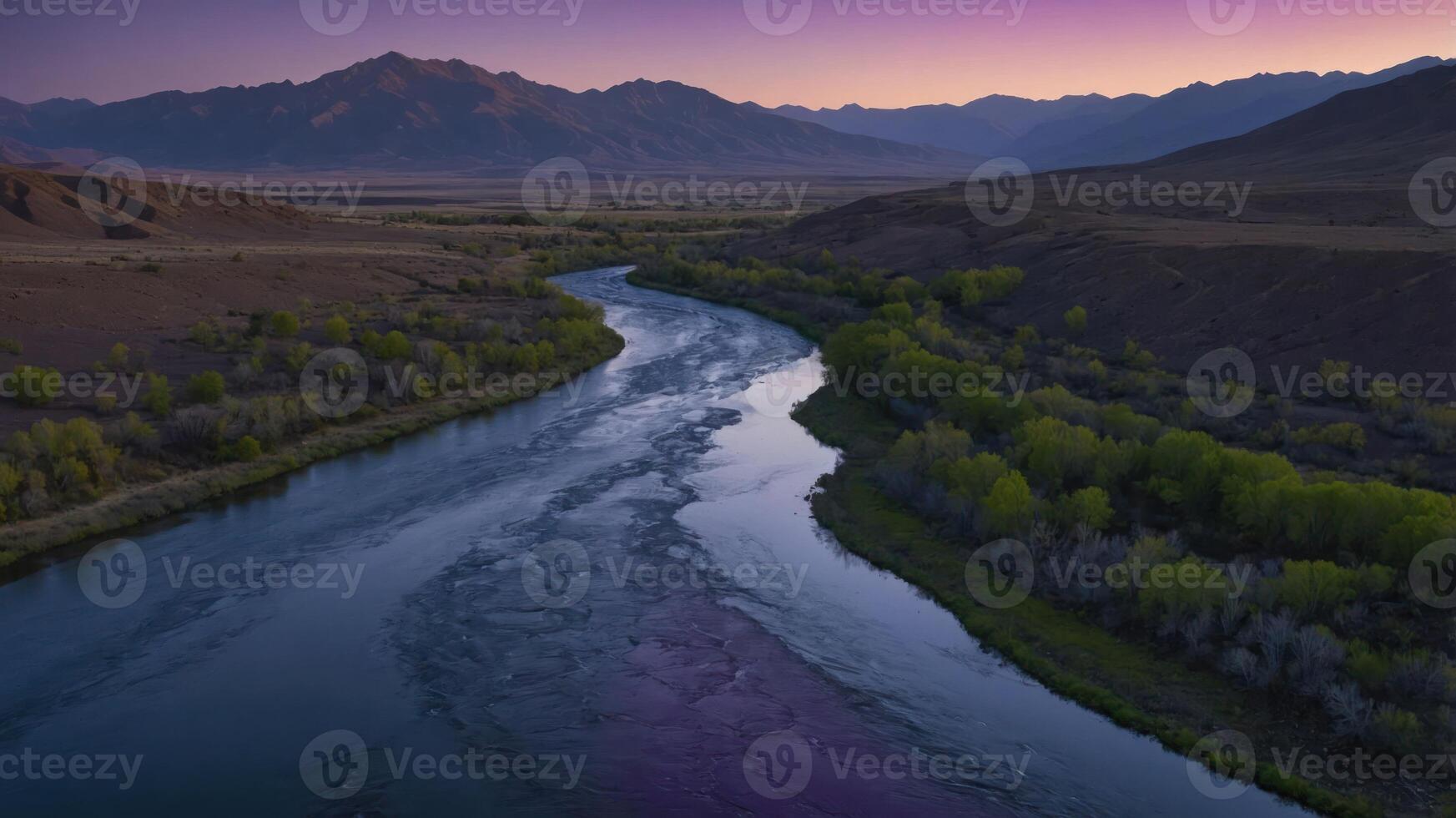A serene river winding through mountains at dusk, reflecting twilight colors. photo