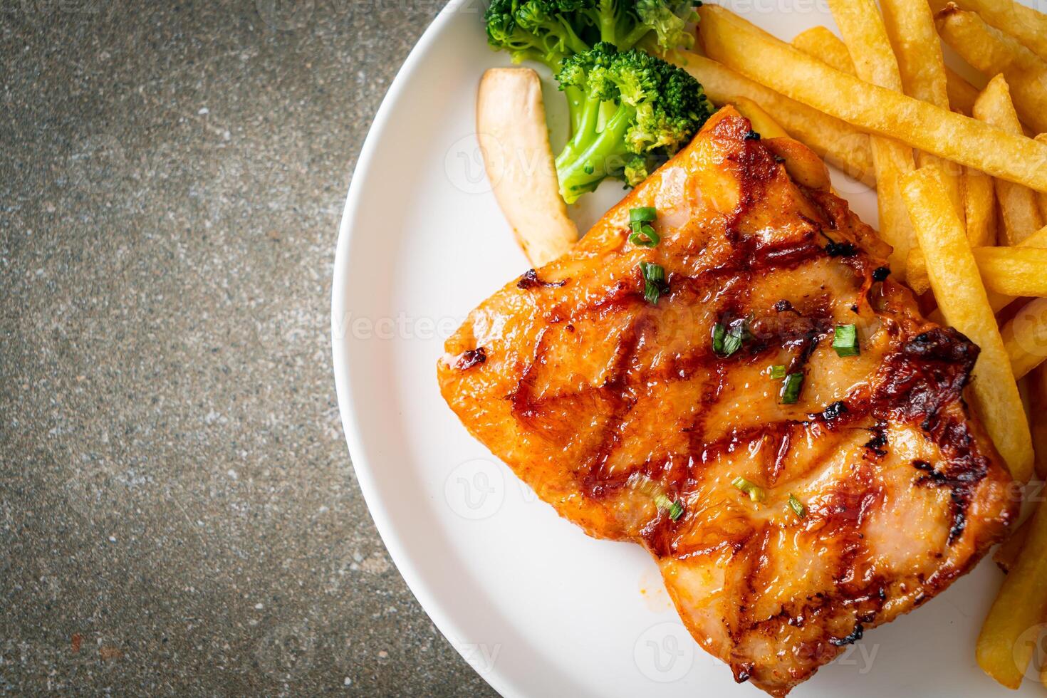 grilled chicken steak with potato chips or french fries on plate photo