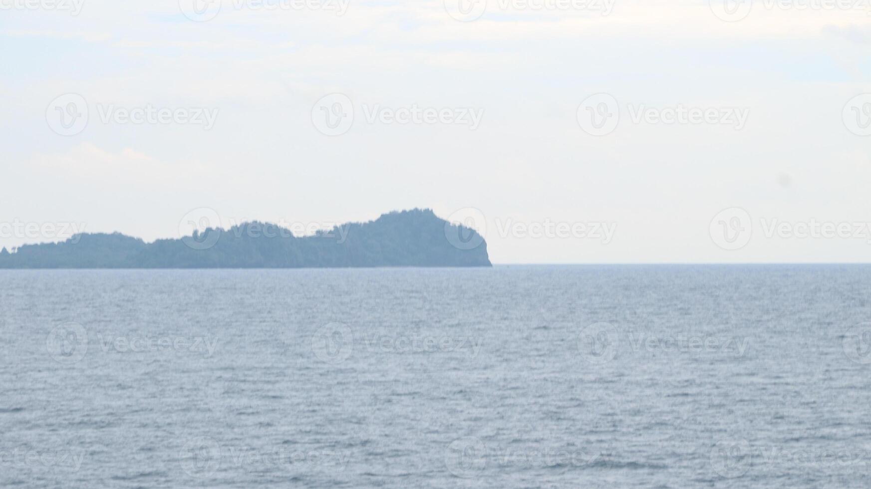 The ocean is calm and the waves are small. The water is a beautiful shade of blue. The sky is clear and the sun is shining photo