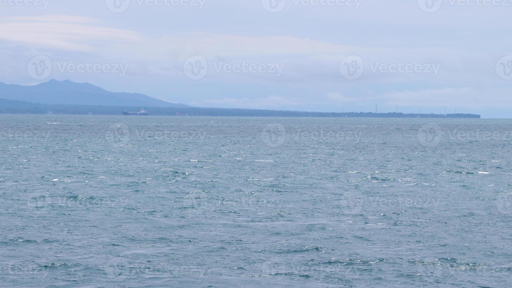 The ocean is calm and the waves are small. The water is a beautiful shade of blue photo