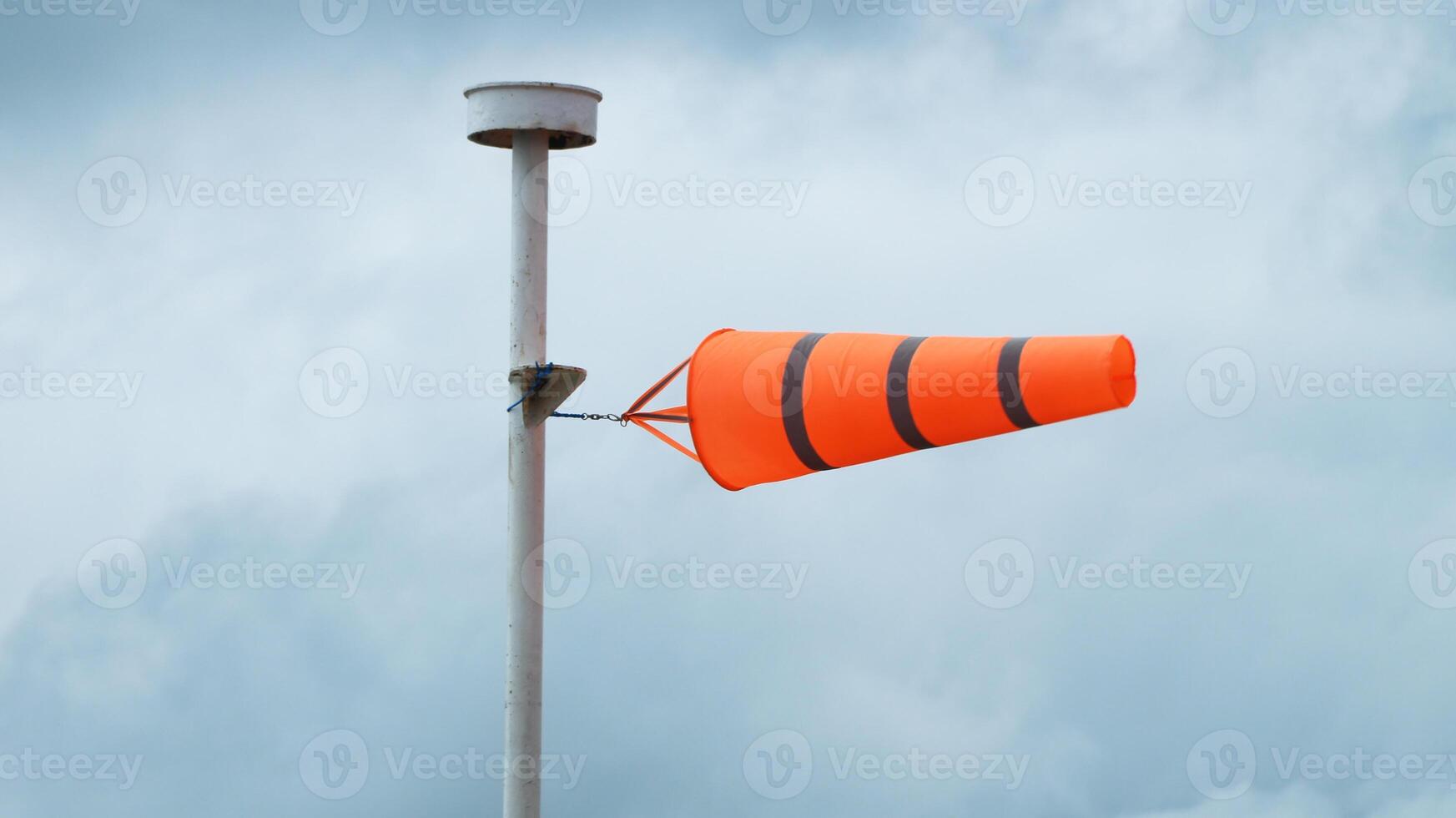 Windsock indicator of wind on tank chemical cone indicating wind direction and force. Horizontally flying windsock with cloud sky in the background.. photo