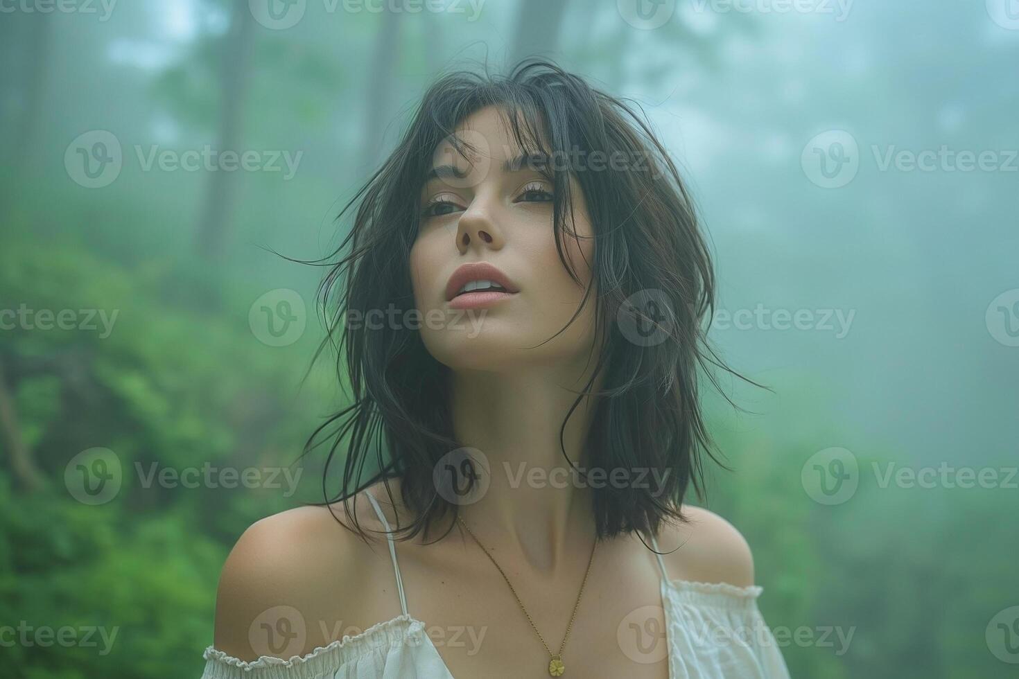 A young woman with dark hair stands serenely in a misty forest, embodying tranquility and connection with nature. photo
