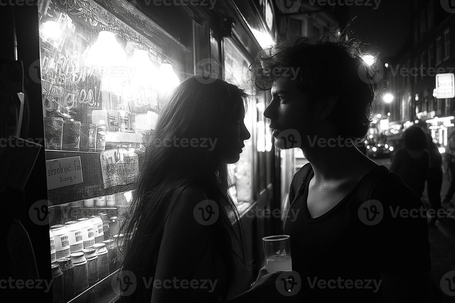 A romantic moment captured in silhouette, featuring a young couple, as they share an intimate gaze at night. photo