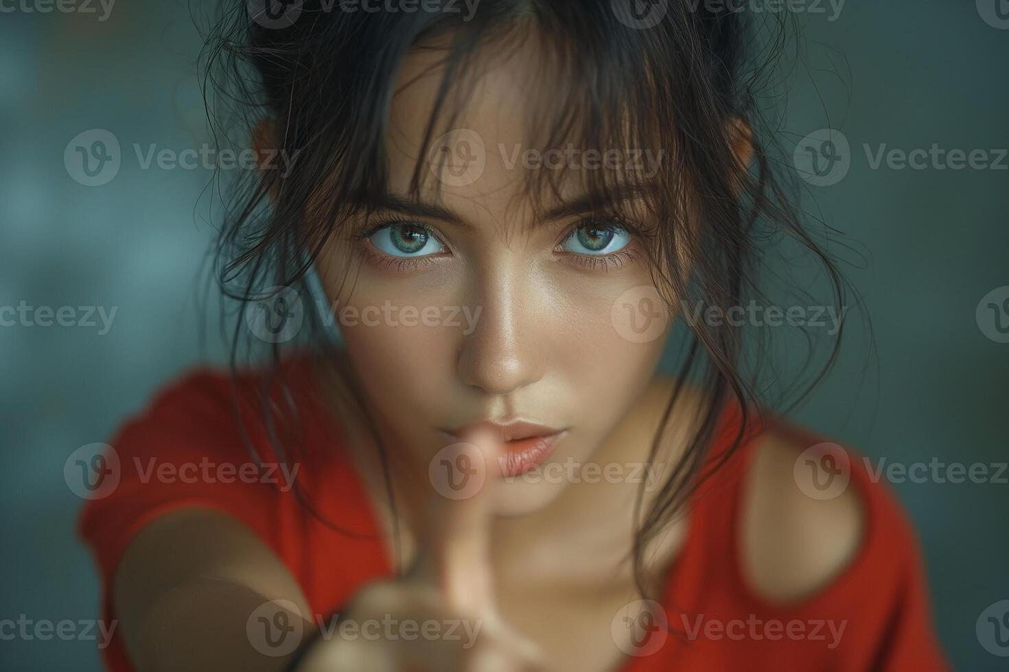 A young Asian woman with striking blue eyes gestures with her finger, conveying a sense of urgency and focus in a soft, muted backdrop. photo