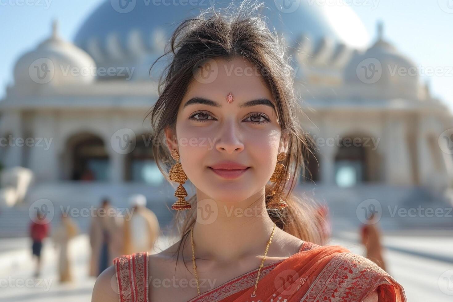 A beautiful young South Asian woman wearing traditional attire, smiling in front of an ornate building. photo