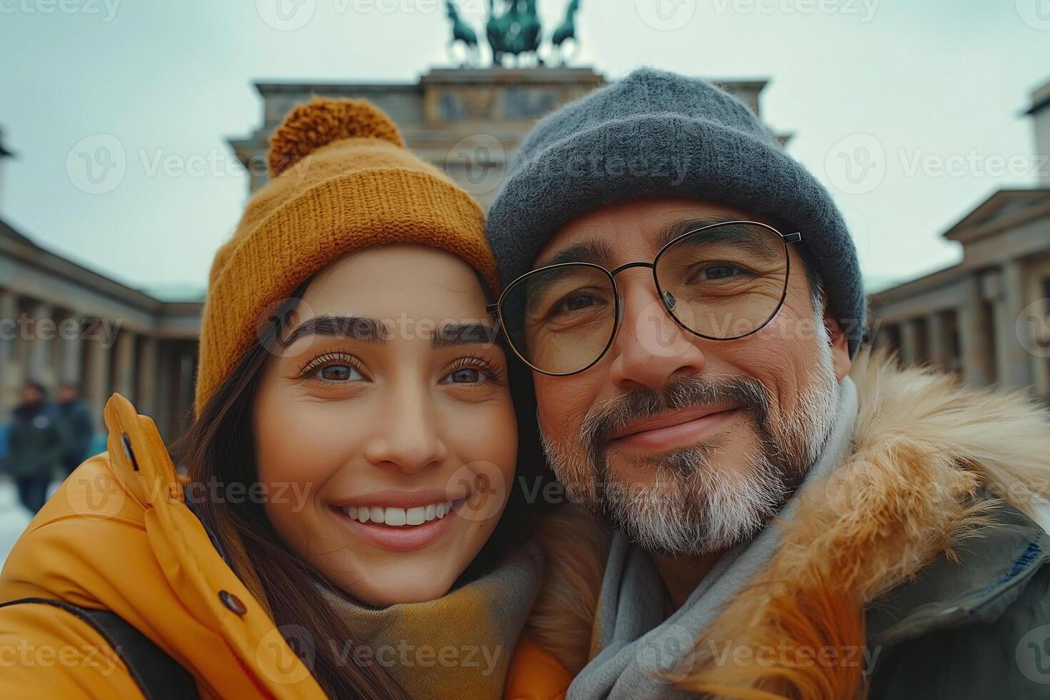 A joyful young woman of Latina descent and a mature man enjoying a moment at a historic monument, both bundled up in warm, cozy attire. photo