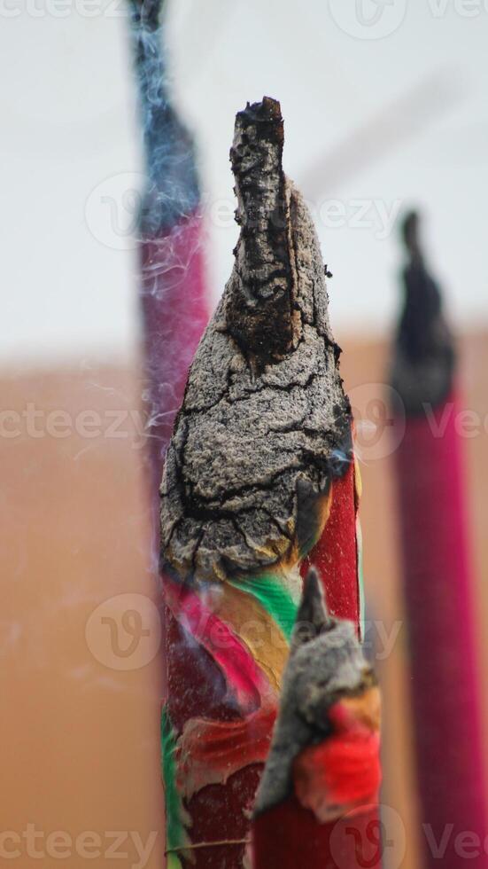 Thick, towering incense sticks burn brightly in front of the temple, releasing fragrant smoke that fills the air. photo
