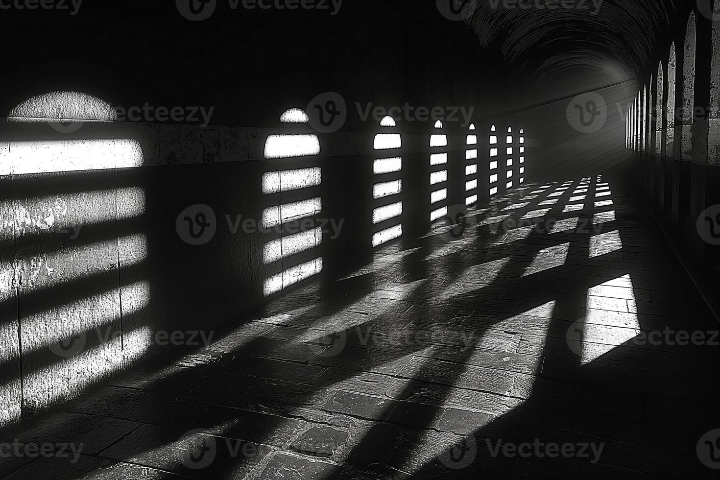 A dramatic monochrome view of a long, shadow-filled corridor with arching windows casting light patterns. photo