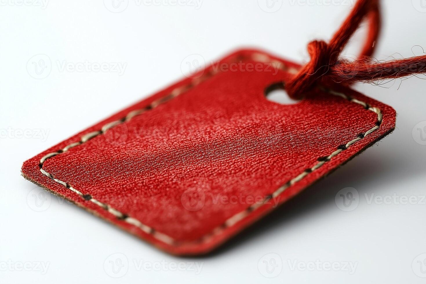 Close-up of a red leather tag with a textured surface and a string, ideal for branding or pricing. photo