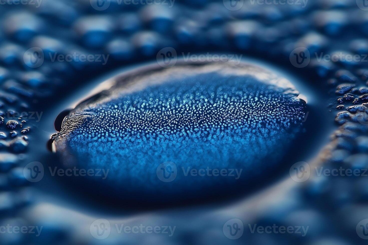 A close-up shot of a water droplet on a blue surface, showcasing a mesmerizing array of tiny bubbles. photo