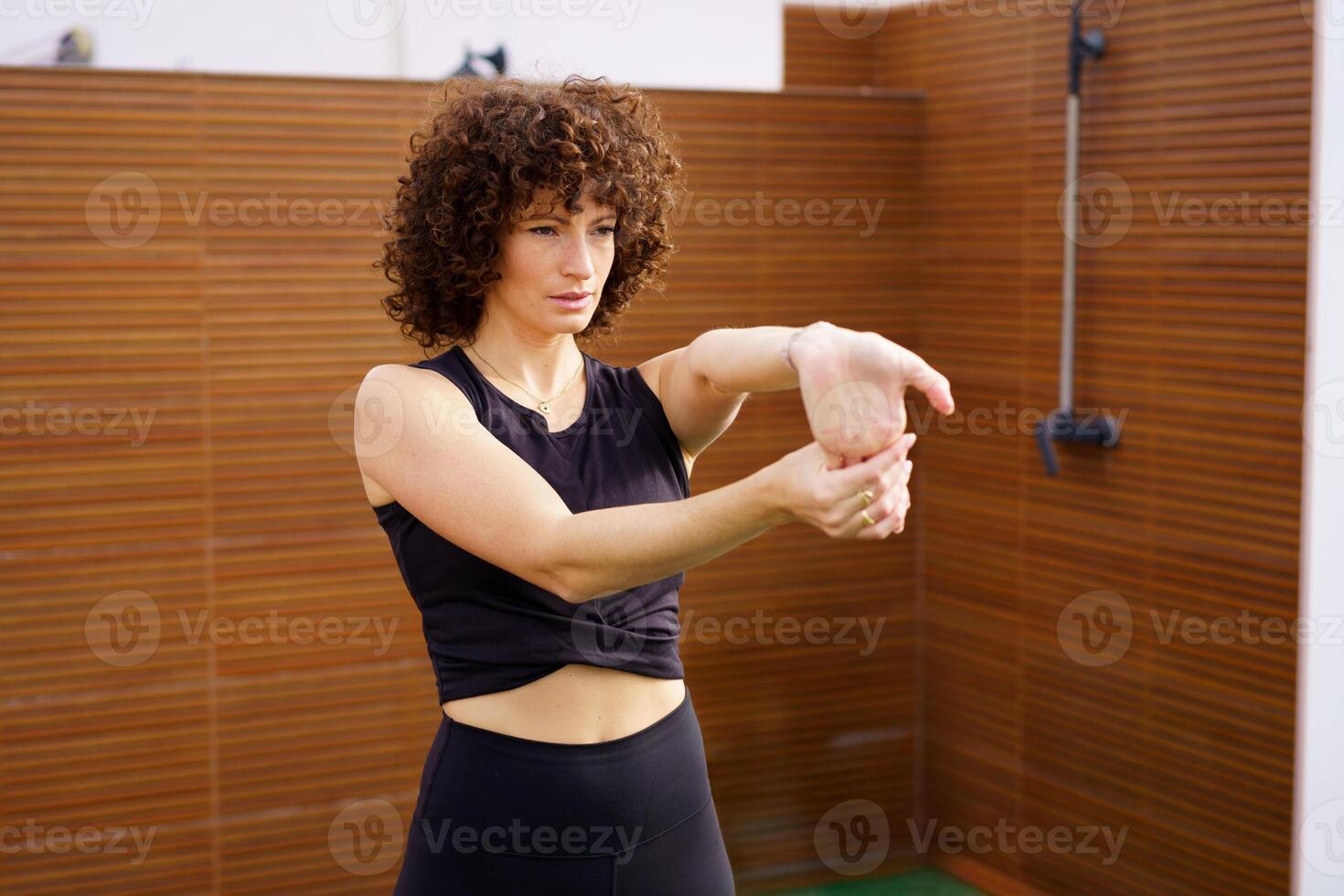 A woman is stretching her arm in a modern and wellequipped fitness studio environment photo