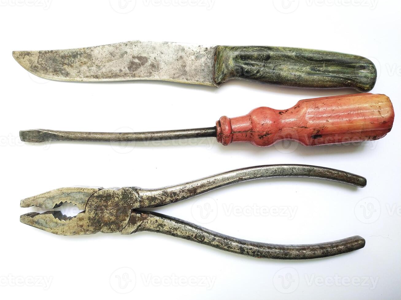 Aged tools a knife, screwdriver, and pliers, arranged on a white background. Evokes nostalgia, DIY, and craftsmanship. Perfect for projects about repair, vintage items, or manual labor. photo