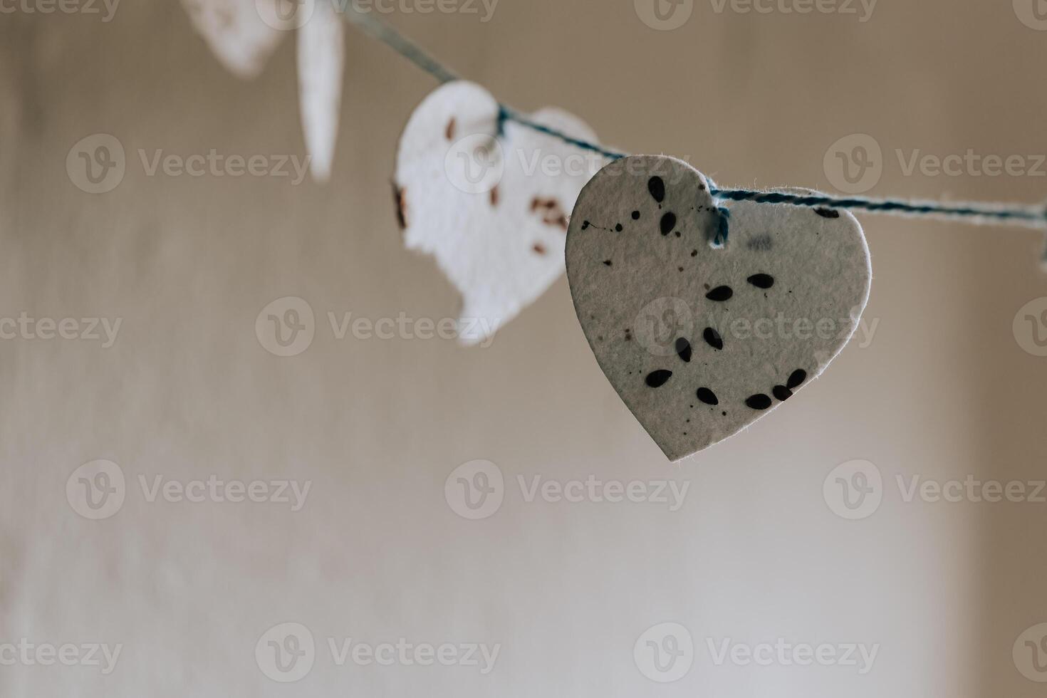 Decorative paper hearts hanging on a string in a softly lit indoor space photo