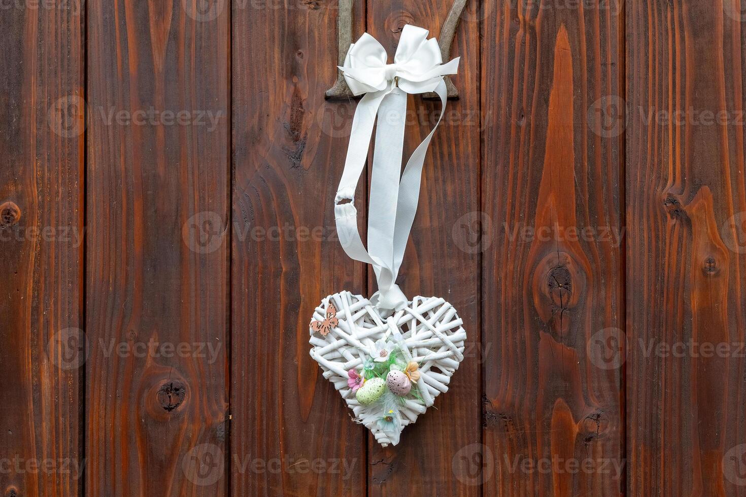 Decorative heart-shaped ornament hanging from wooden wall showcasing intricate design with natural elements photo