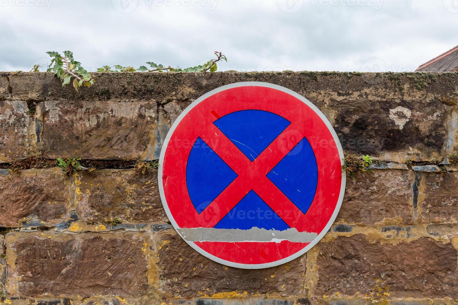 No parking sign mounted on a stone wall in an urban area reflecting local regulations photo