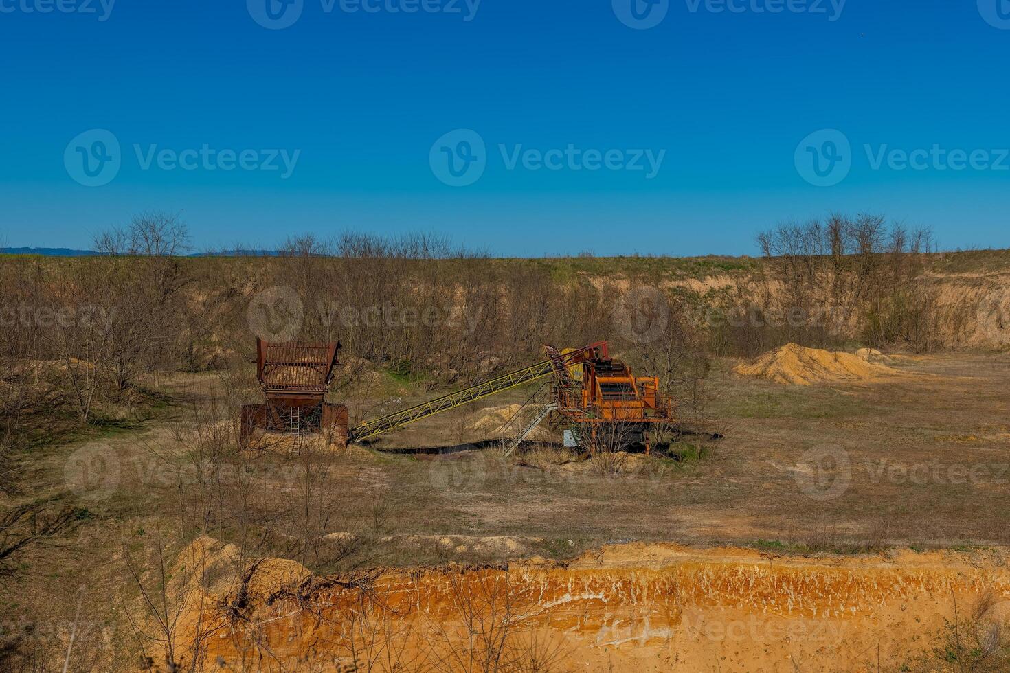 Abandoned mining equipment in a barren landscape during bright daylight at a remote location photo