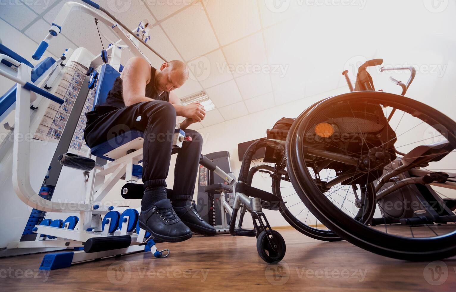 Disabled man doing strength exercises separate from the wheelchair. photo