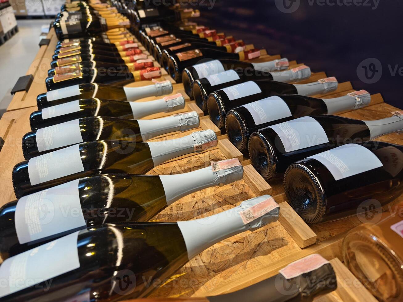 A variety of bottles of champagne are elegantly lined up on a wooden shelf photo