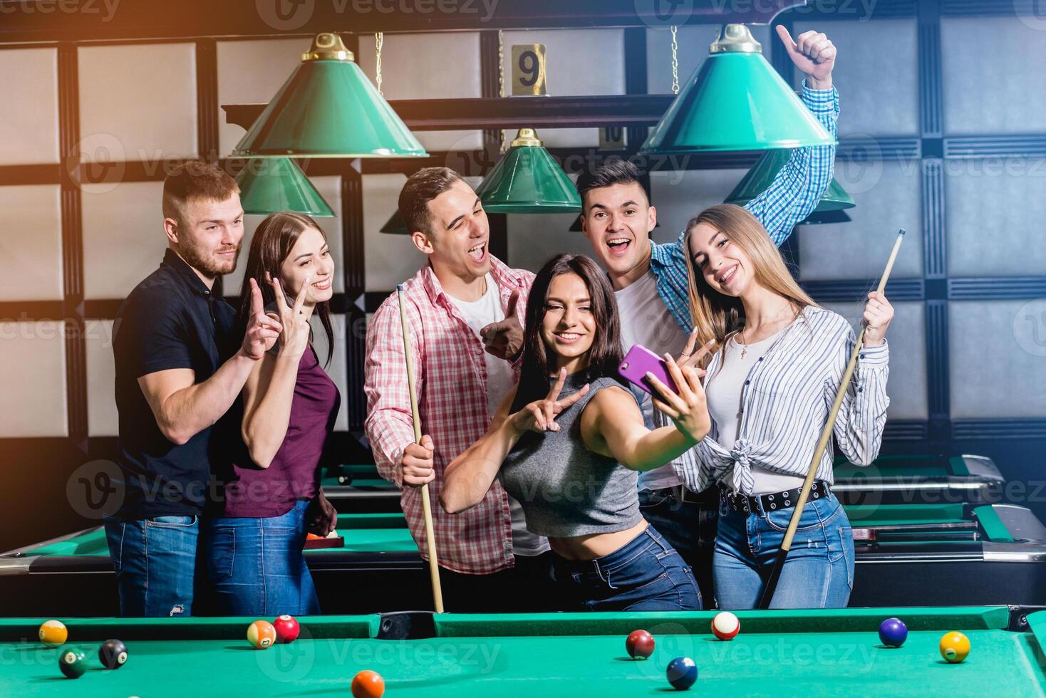 A group of friends makes a selfie at the pool table. photo