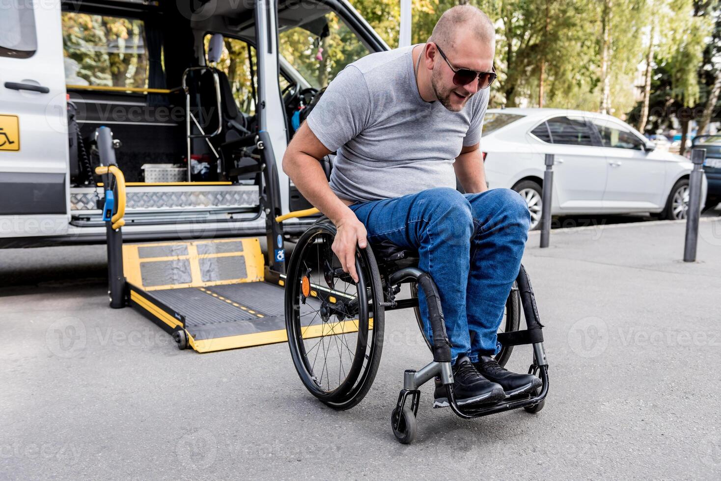A man in a wheelchair on a lift of a vehicle for people with disabilities photo