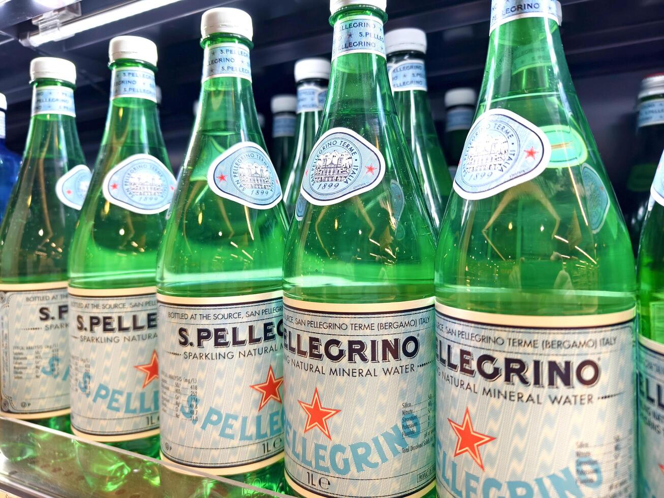 PHUKET, THAILAND - MARCH 8, 2025. Bottles of S.Pellegrino mineral water are neatly lined up on a shelf photo