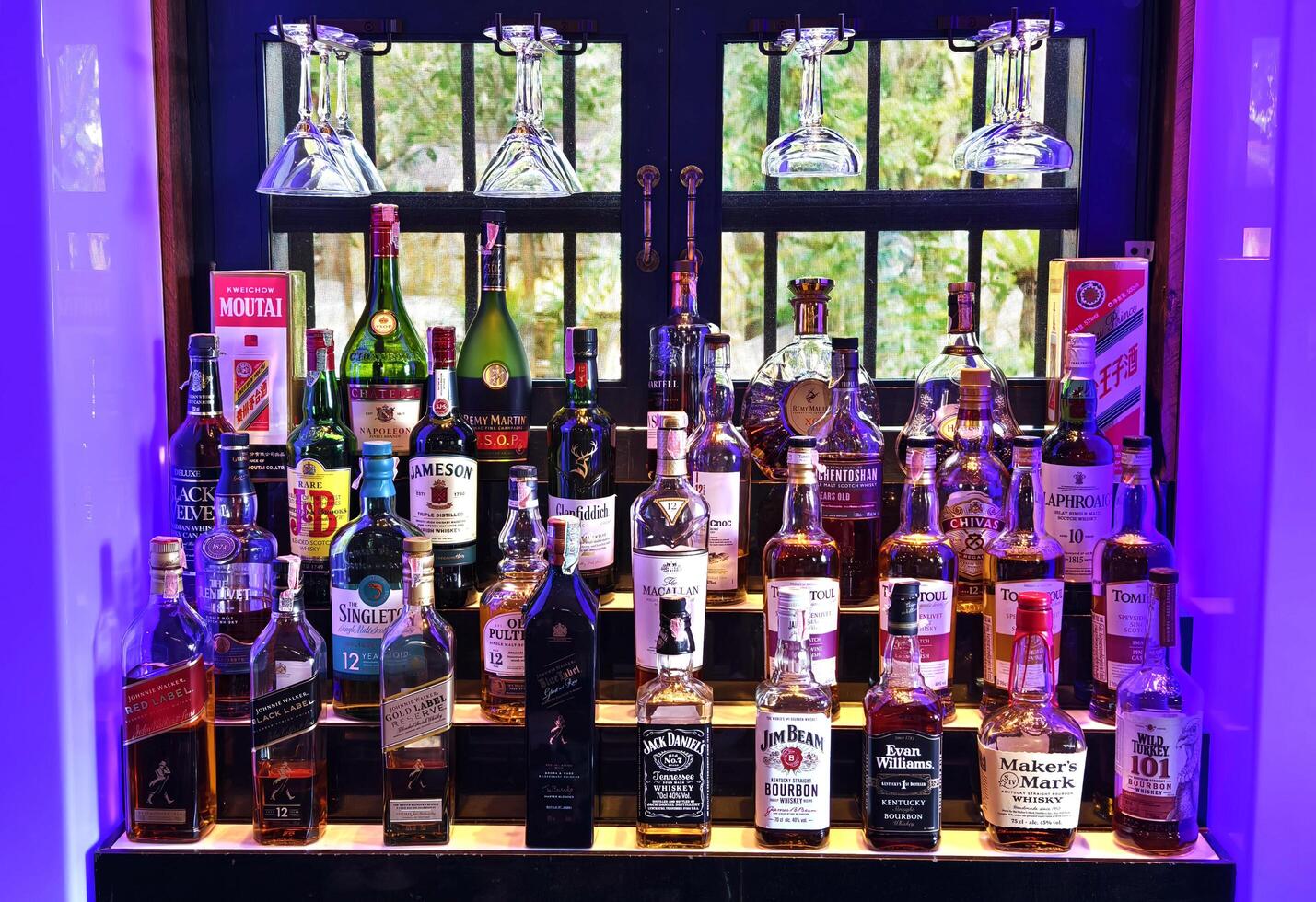 PHUKET, THAILAND - MARCH 8, 2025. Many bottles of wine neatly arranged on a bar shelf photo