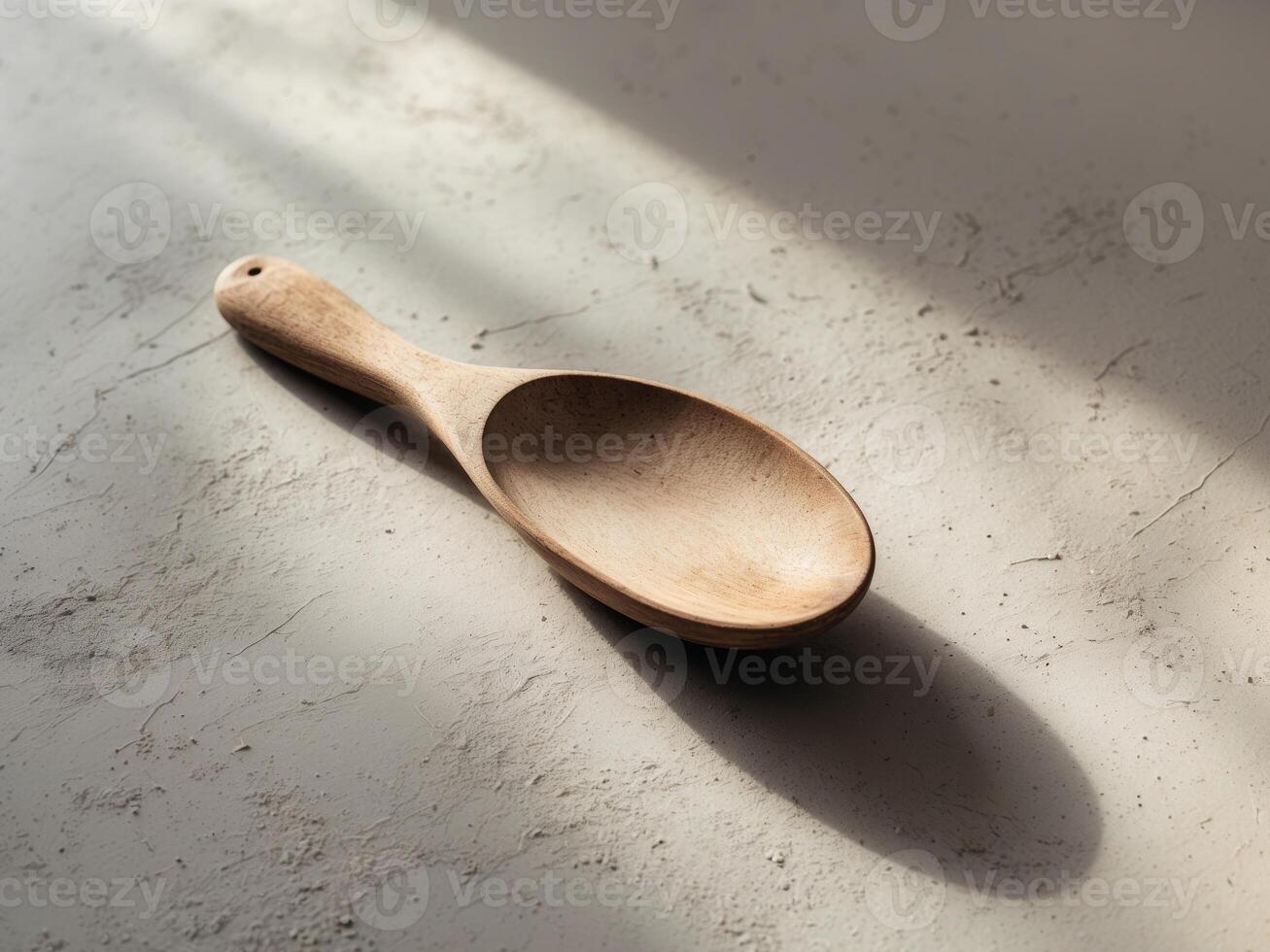 Wooden Spoon on Textured Gray Surface with Shadow photo