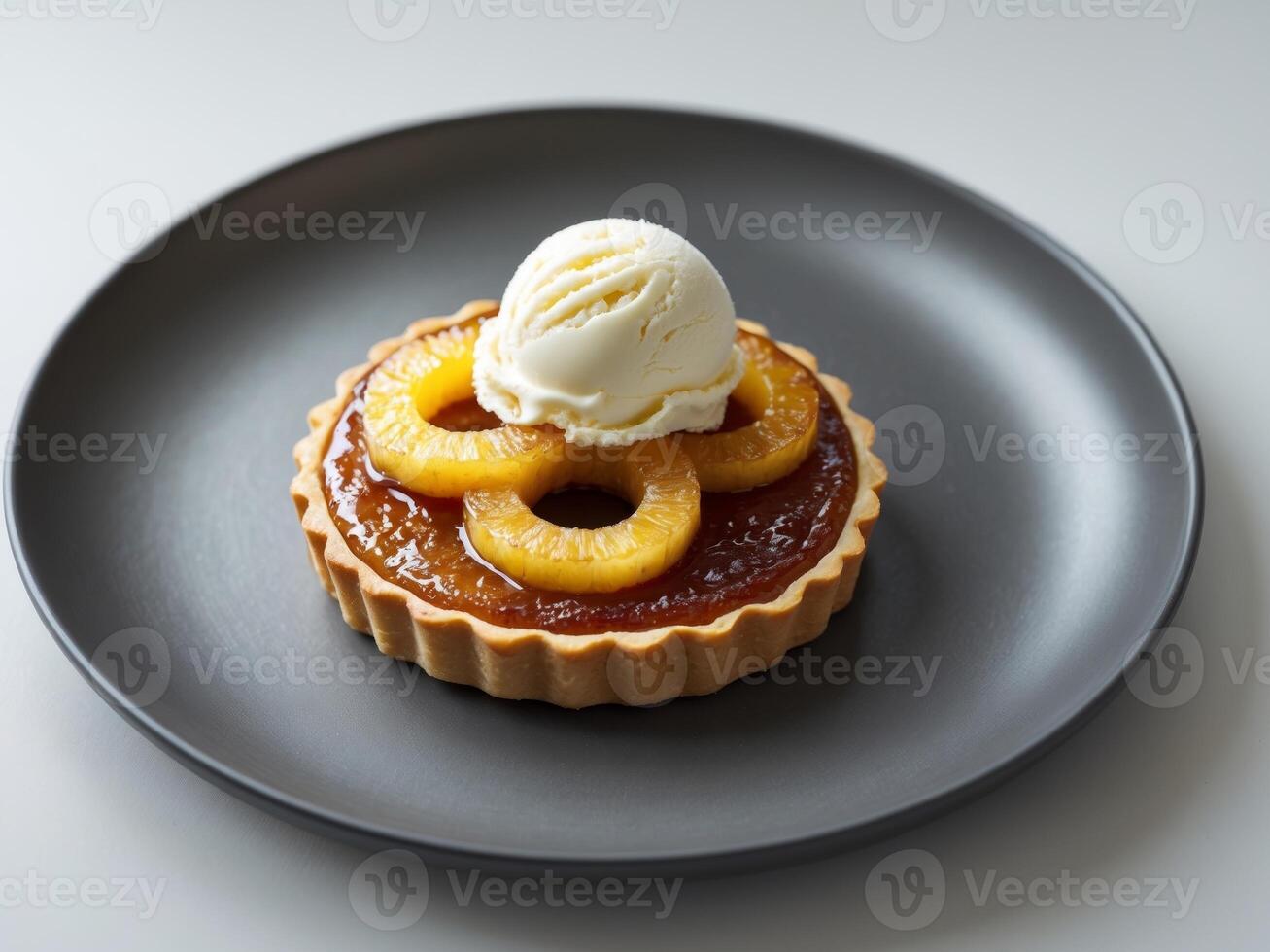 Delicious caramelized pineapple tart with creamy vanilla ice cream served on a dark plate. photo