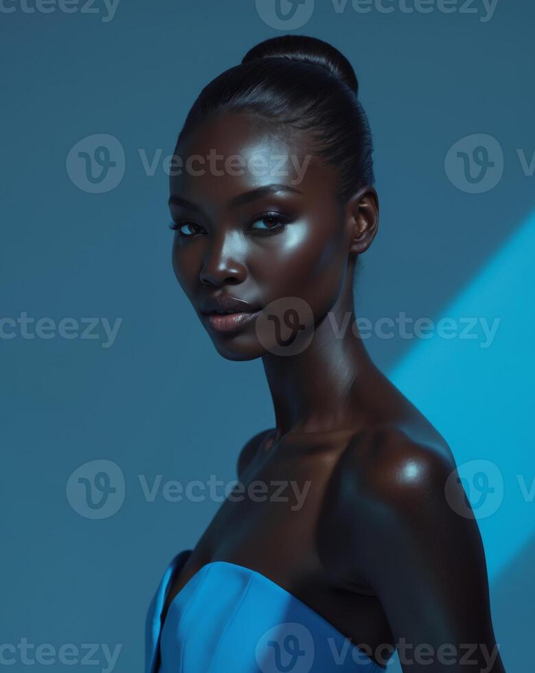 Beautiful black model posing with glowing skin on blue background. photo