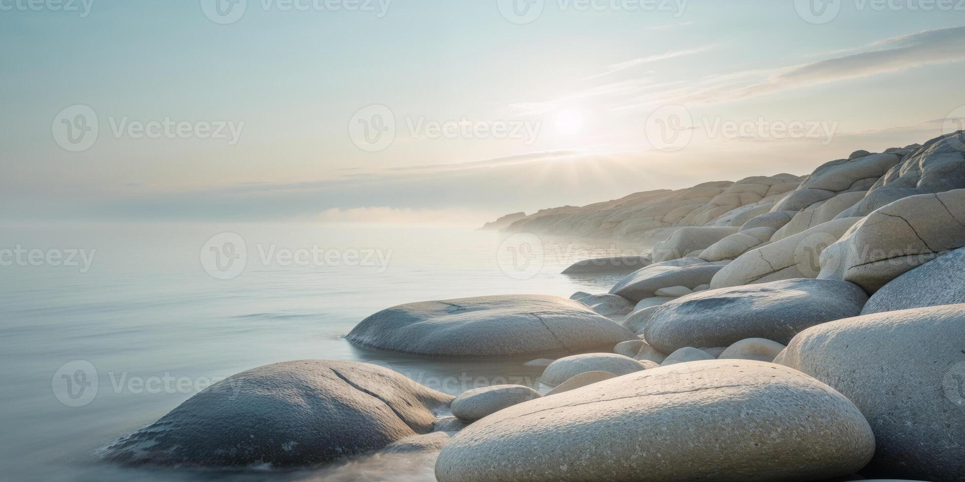 Calm coastal scene featuring smooth rocks and a diffused sun photo