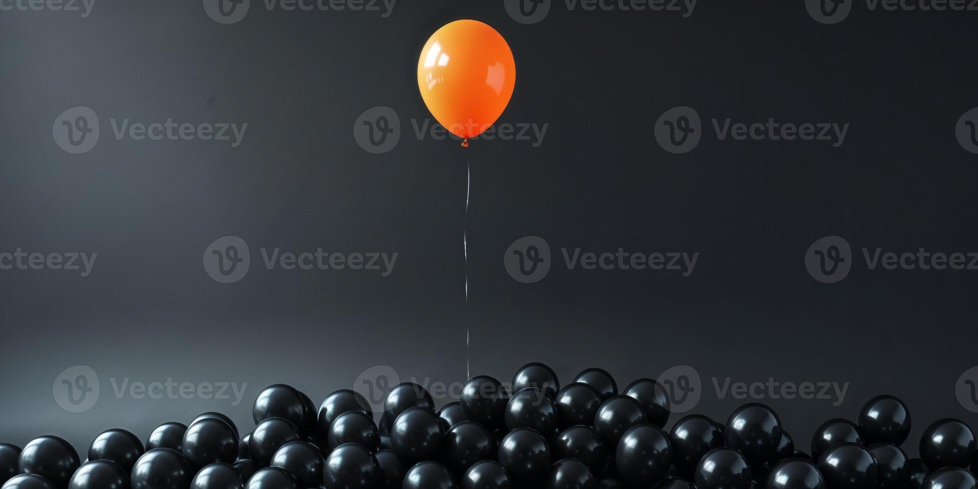 Orange balloon rising above many black balloons on dark background photo