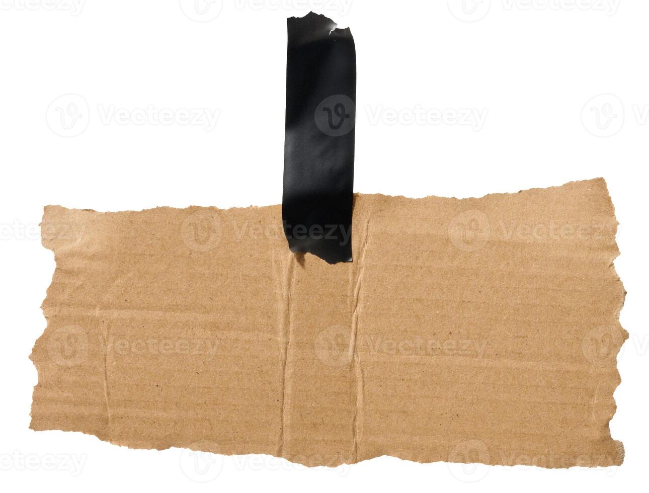 Torn piece of brown corrugated cardboard attached to black piece of electrical tape, isolated background photo
