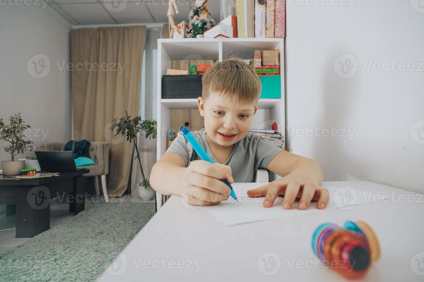 smiling boy focused on drawing at his study desk in a bright room, concept of early education, creativity in children, home schooling photo