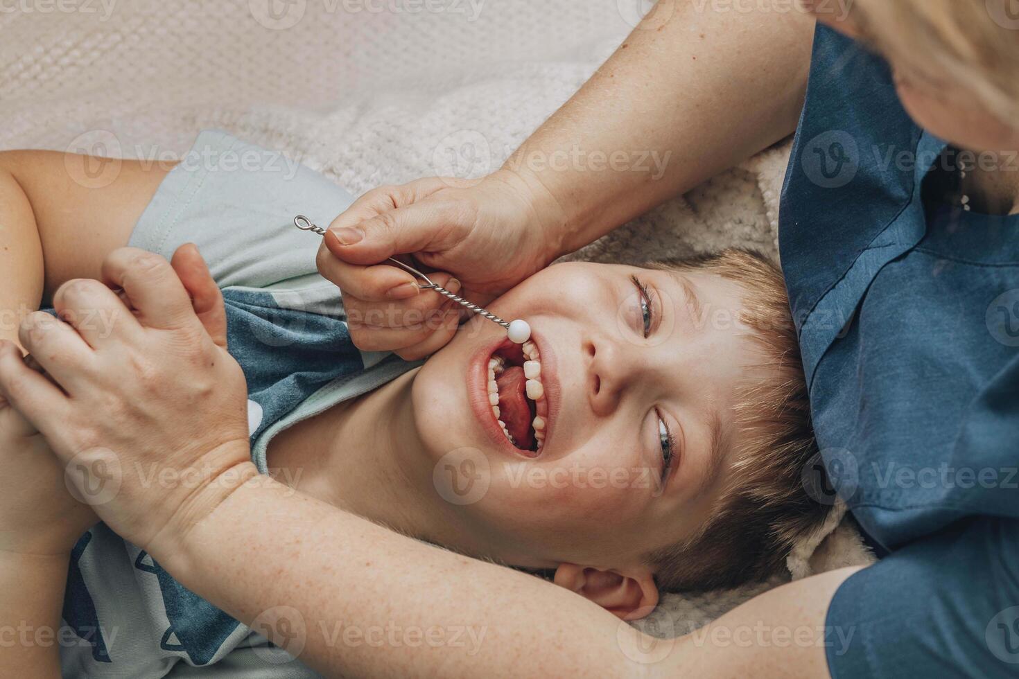 boy lying on soft white blanket during speech therapy session with female therapist in cozy room, concept of speech correction, childhood development, and healthcare, close up photo