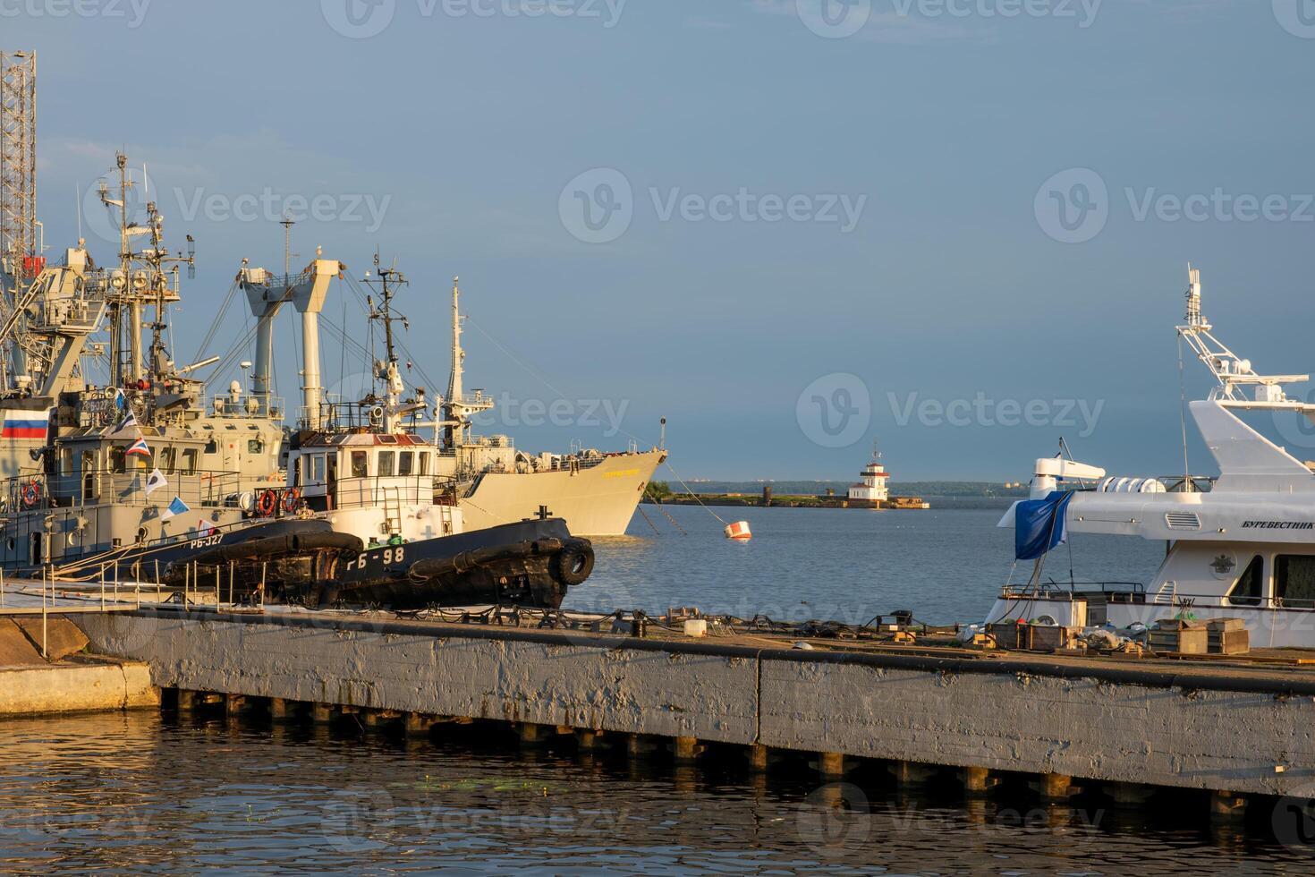 Kronstadt, Russia - 07.27.24. Harbor View with Ships and Lighthouse in Distance. photo