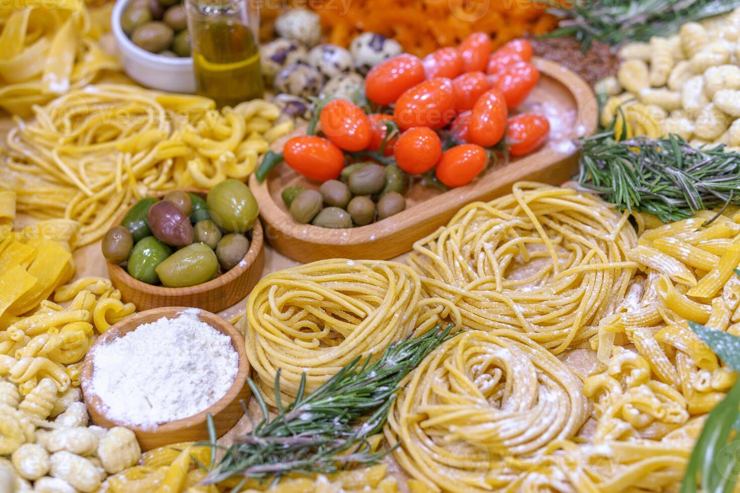 A table full of food including pasta, olives, tomatoes, and quail eggs. The table is set for a meal and the food looks delicious photo