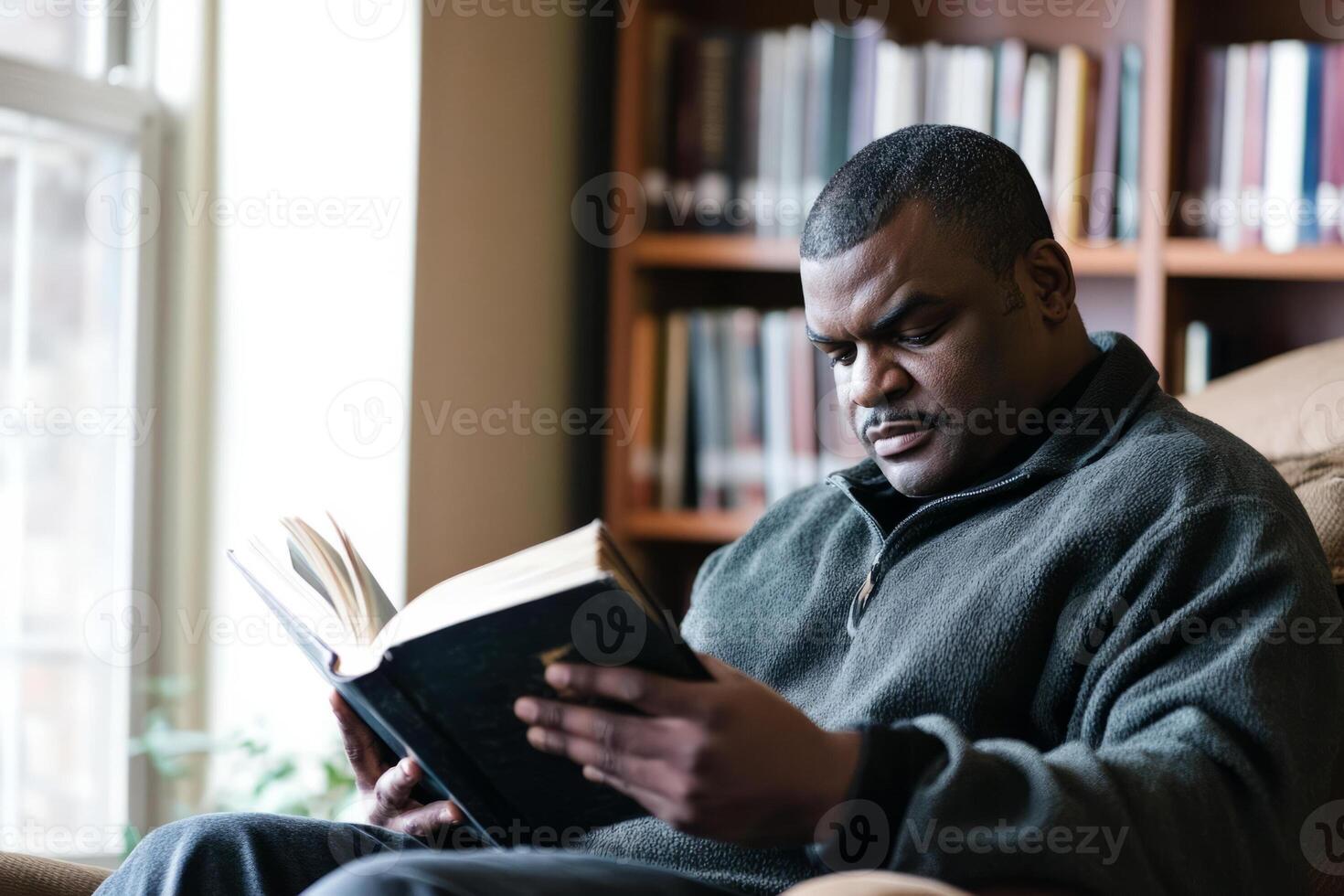A man is reading a book in a chair photo