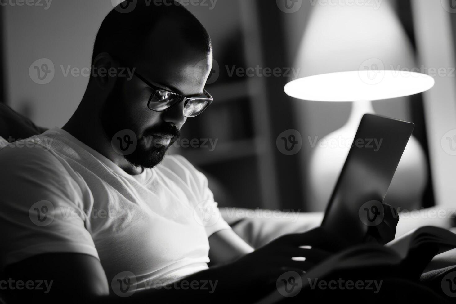 A man with glasses and a beard is using a laptop photo