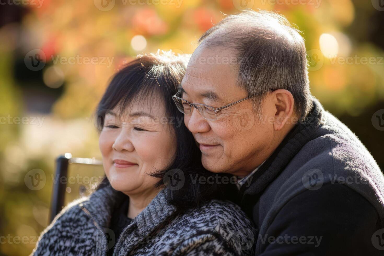 An older couple sitting on a bench in the park photo